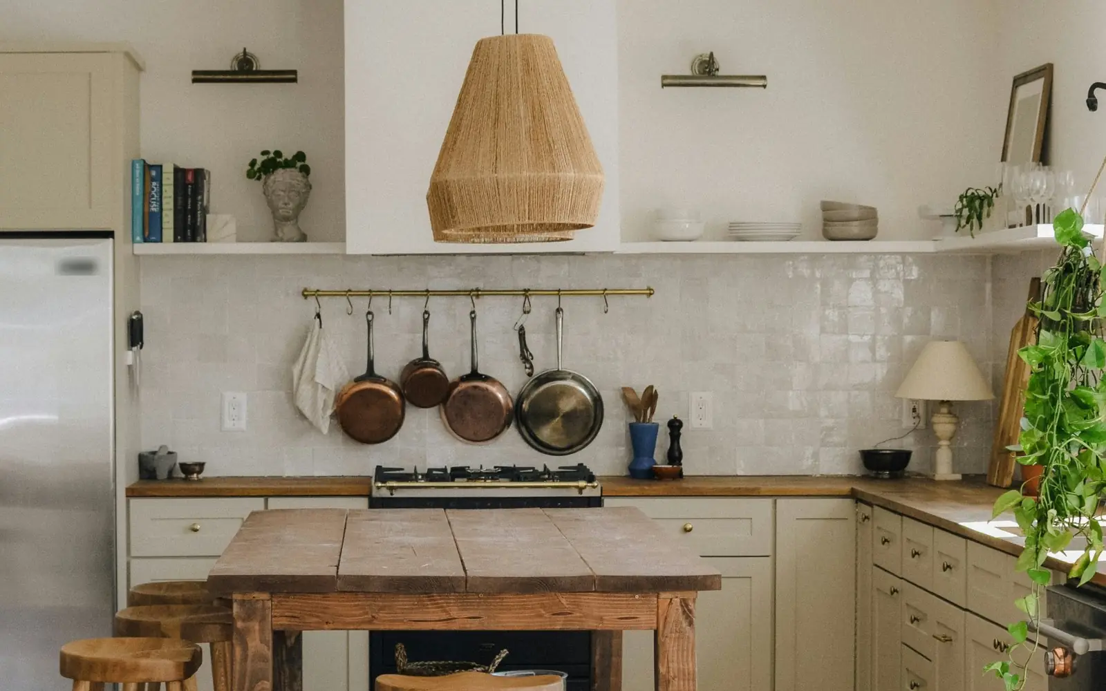 Farmhouse-style kitchen with a wood plank island, butcher block counters, copper pans and a white tile backsplash