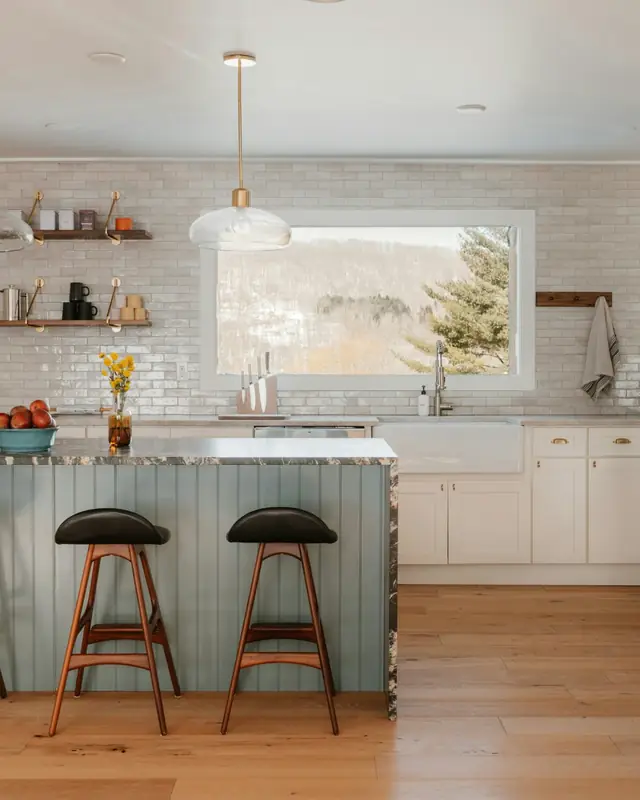 Kitchen with a sage green beadboard island, dark stone waterfall counter, white tile wall and a large range